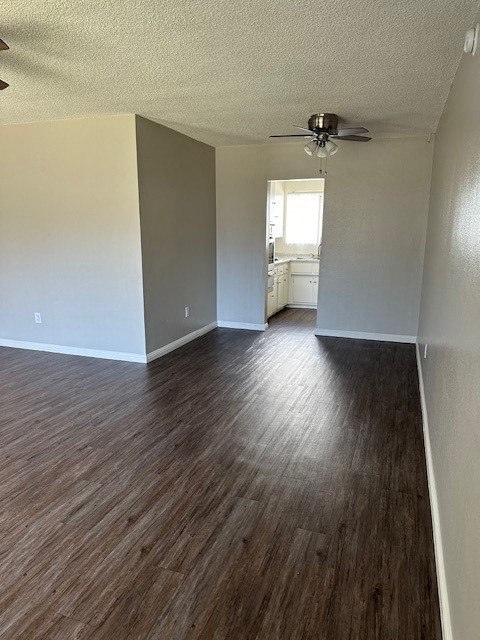 an empty living room with wood floors and a ceiling fan